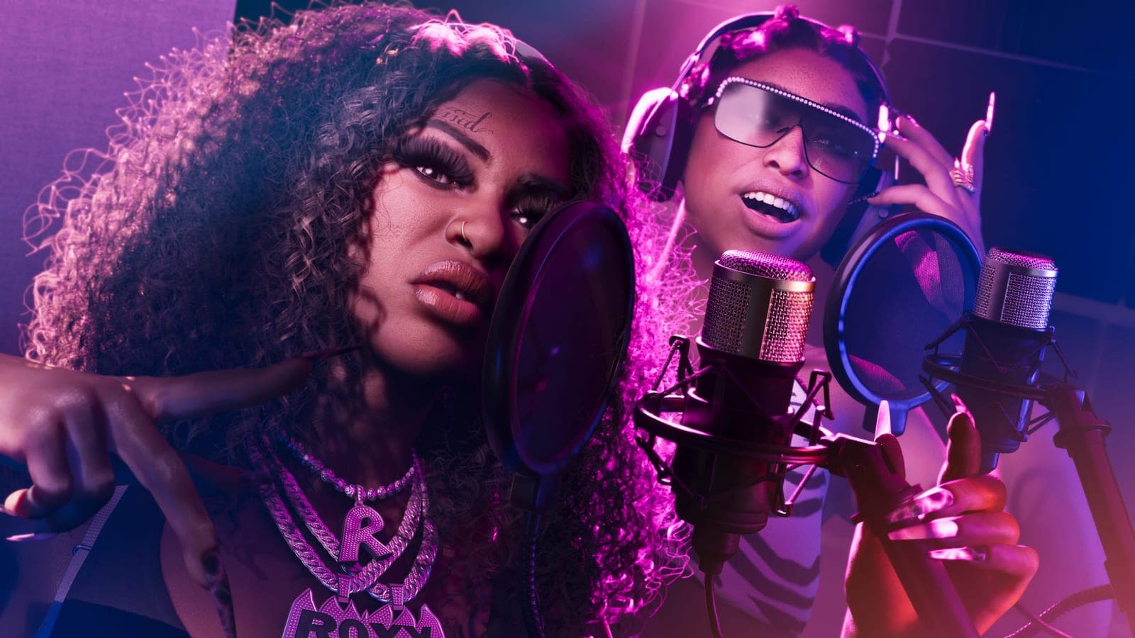 Roxy and Bae-Luxe of Real Dimez at studio microphones under purple light, headphones on, mid-verse.