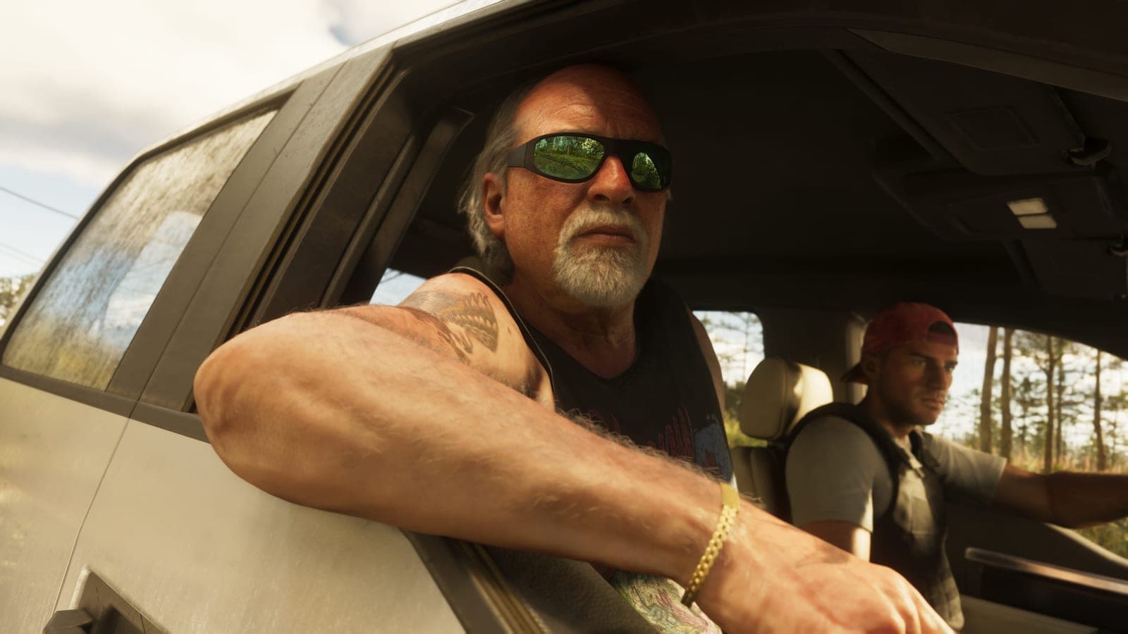 An older man in mirrored sunglasses rests a heavily tattooed arm on a car door, a younger man in a backwards cap driving beside him past pine trees.