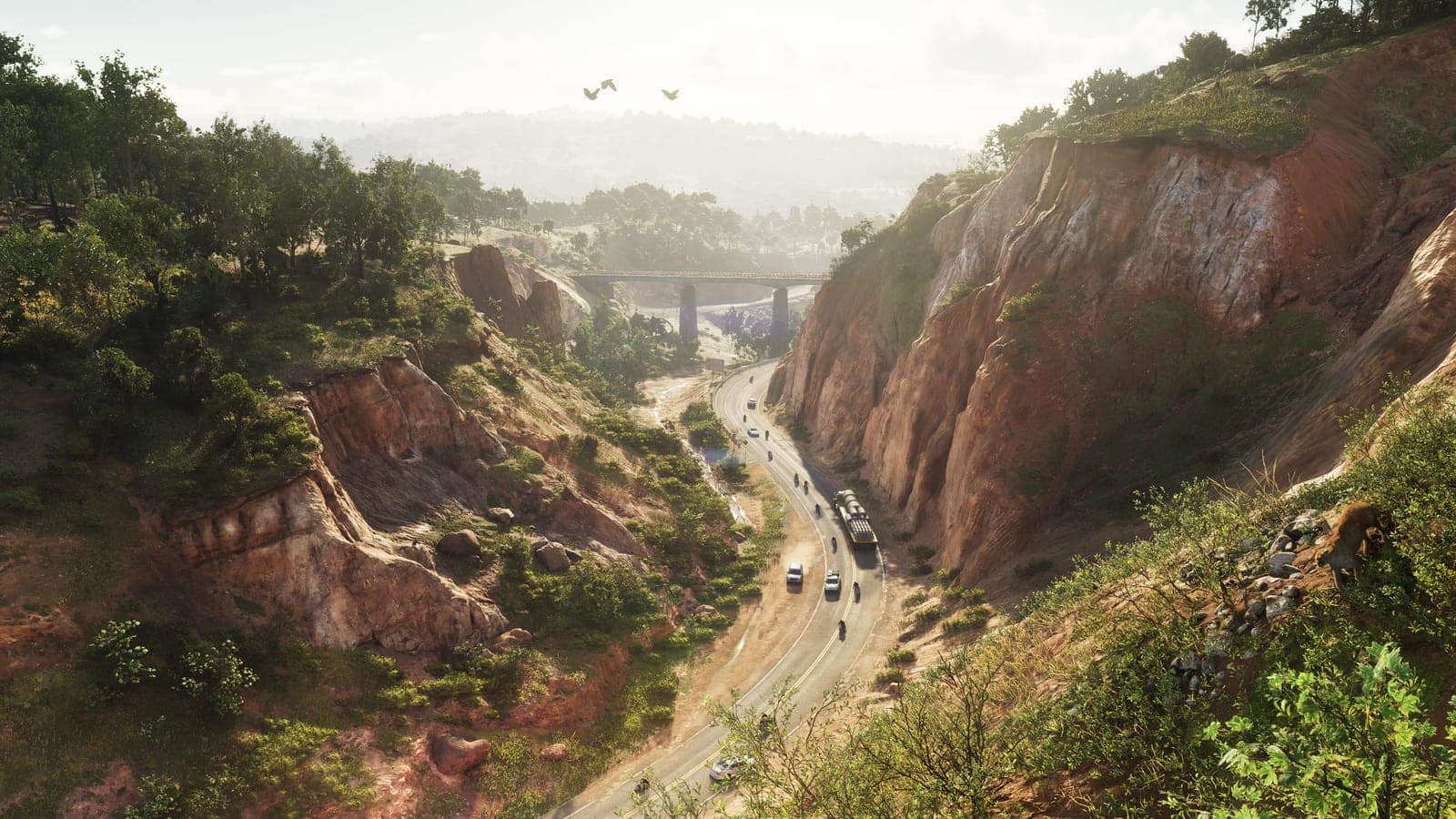 A highway winding through a red-rock canyon in Mount Kalaga National Park, a bridge crossing the gorge ahead and birds over the ridge.