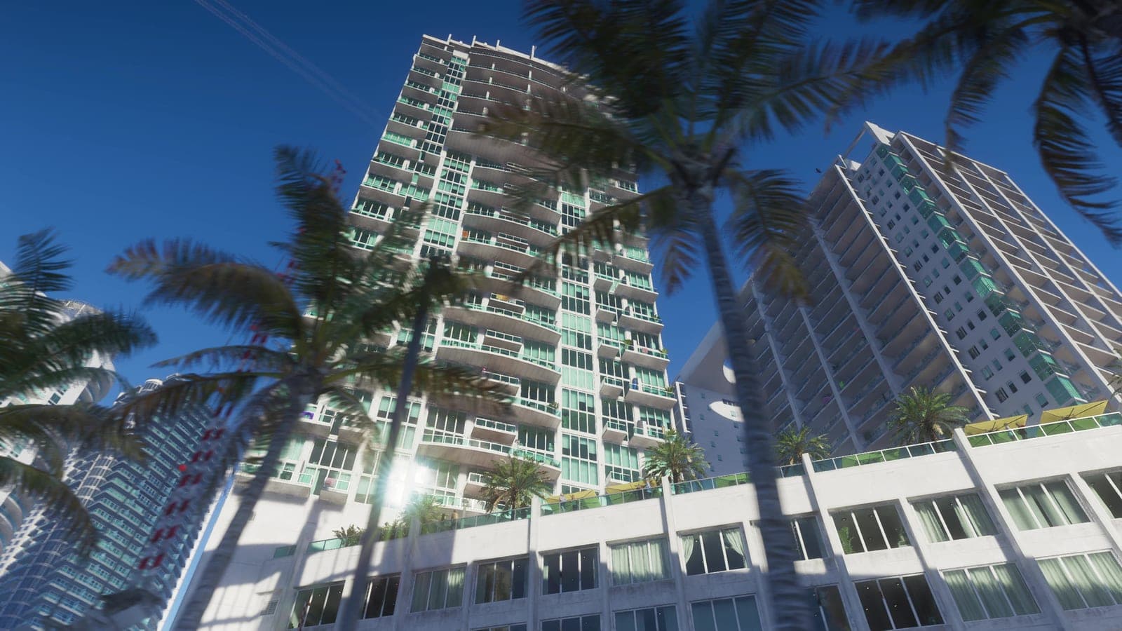 Looking up at glass towers in Vice City against a bright sky.